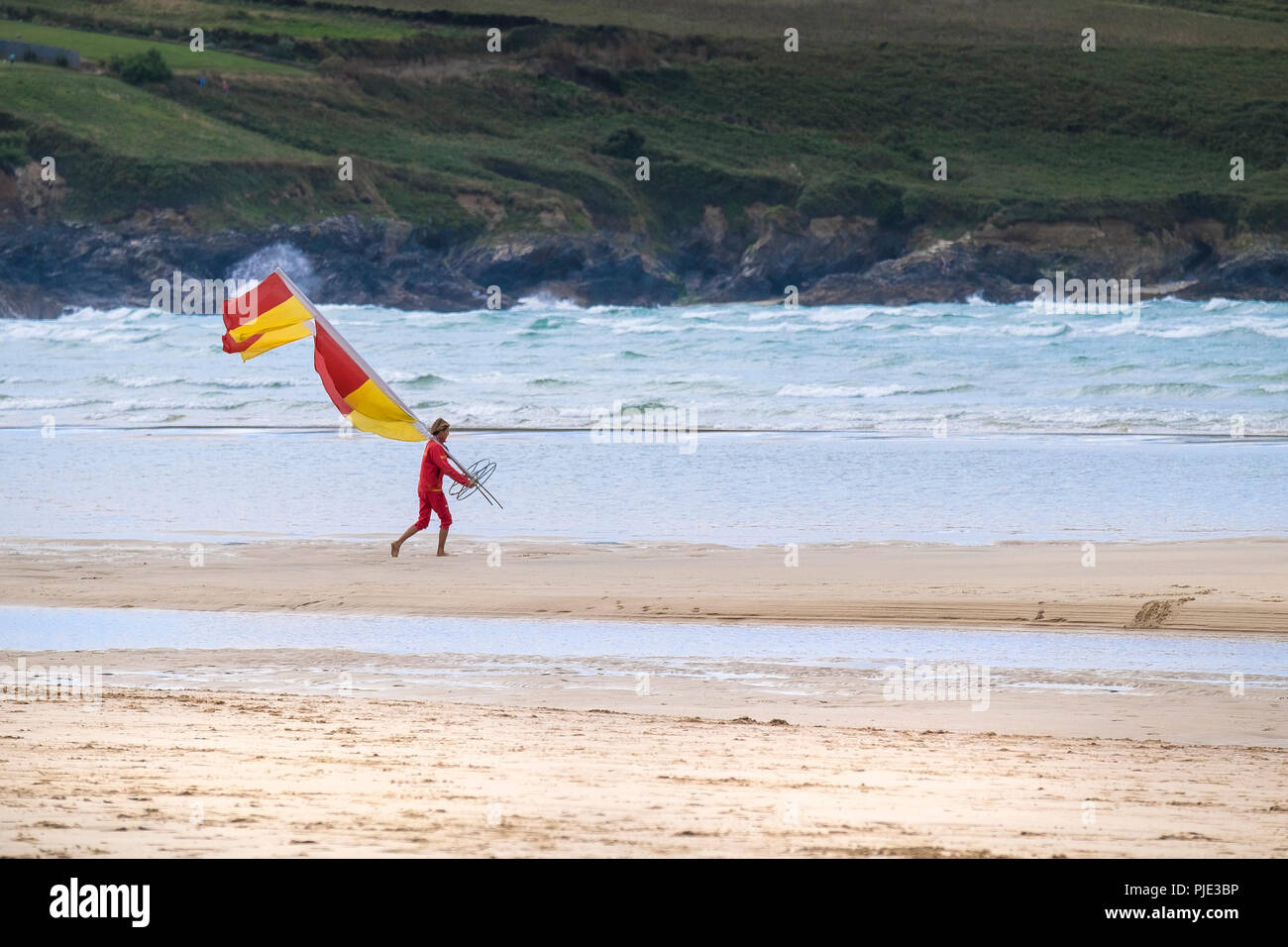 Un bagnino RNLI lo spostamento di un marker di sicurezza bandiera su Crantock Beach in Newquay Cornwall. Foto Stock