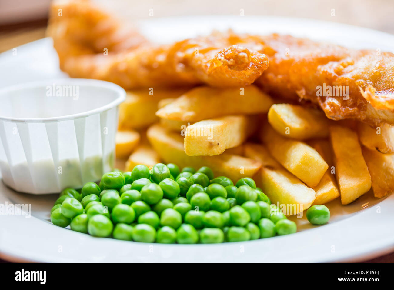 Cibo inglese tradizionale come pesce e patatine fritte con piselli verdi servita nel pub o ristorante Foto Stock