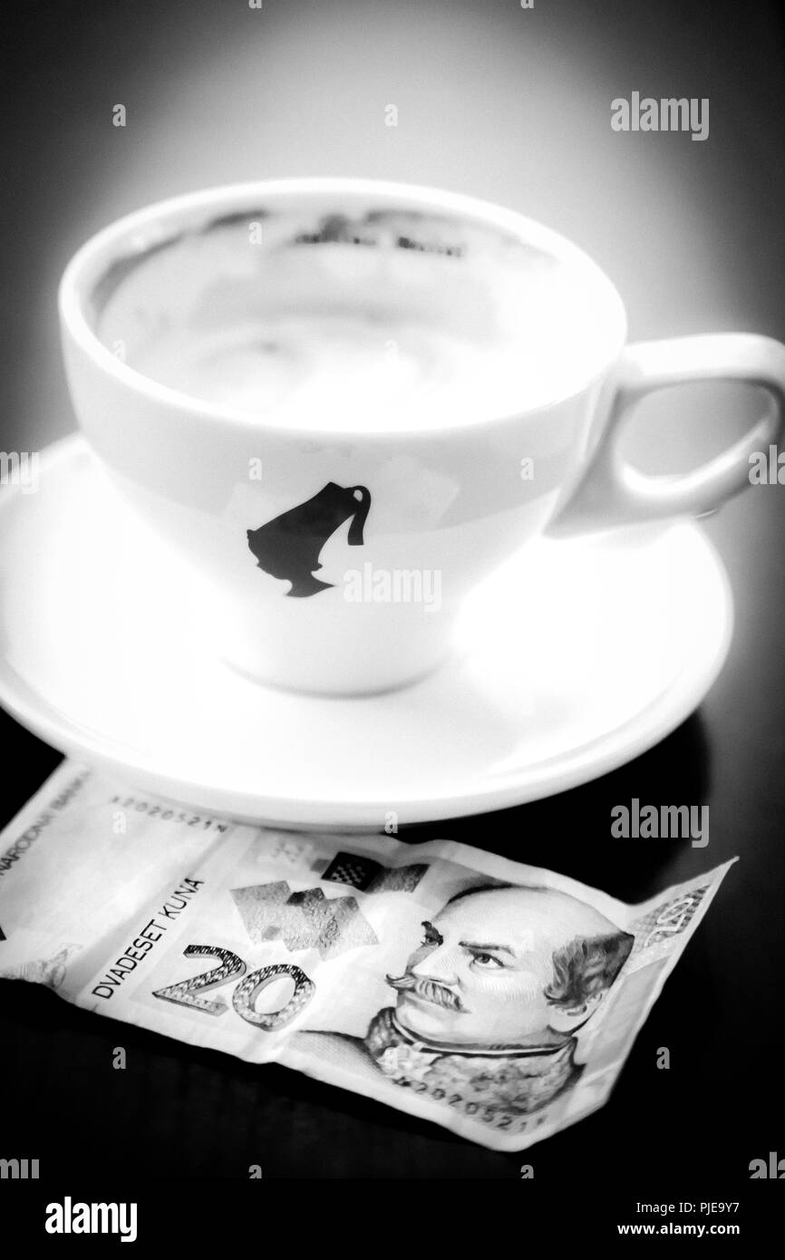 Una solitaria tazza da caffè con piattino con un 20 kune banconota sul tavolo in Croazia Foto Stock