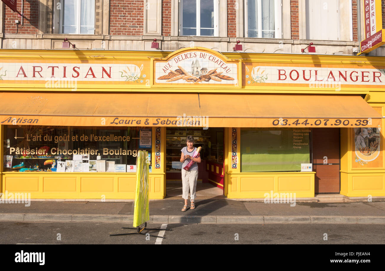 Donna che mantiene la baguette al di fuori di artigiano Boulanger in Bresles, Oise, Francia, Europa Foto Stock