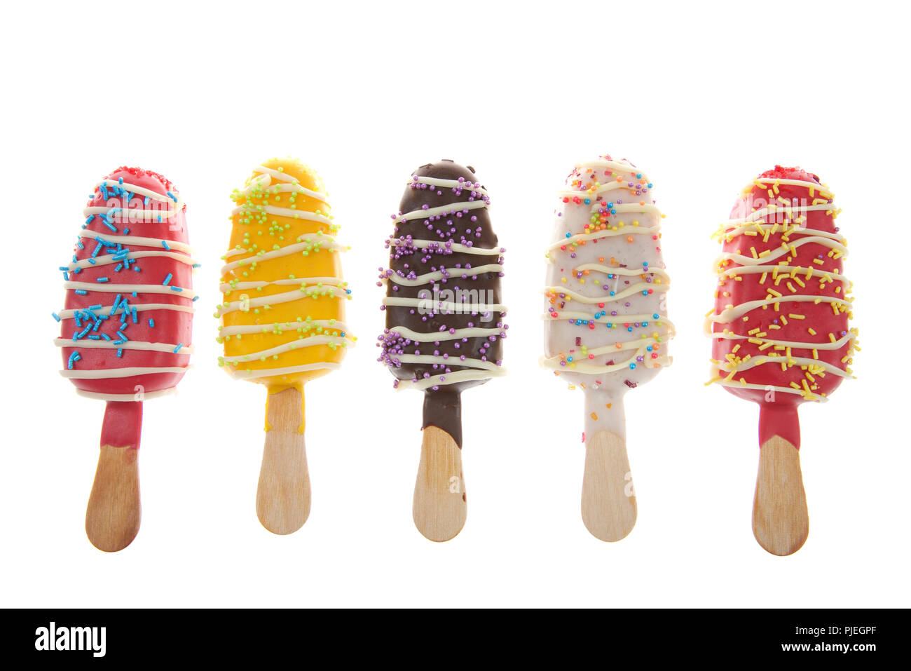 Fila di più caramelle colorate spogliato ghiaccioli cake pops con spruzza sulla cima isolata su sfondo bianco. Divertimento piatti per le feste per bambini Foto Stock