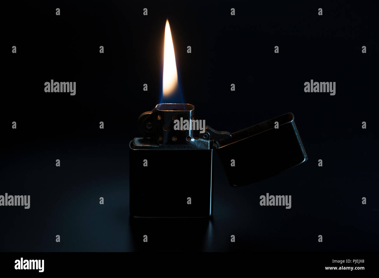 Accendino con fiamma isolati su sfondo nero. Bruciore leggero fluido attraverso un vecchio flip più leggeri. Foto Stock