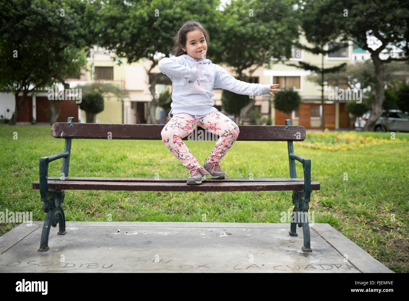 Carino bambina di 5 anni seduto sul banco in un parco. Foto Stock