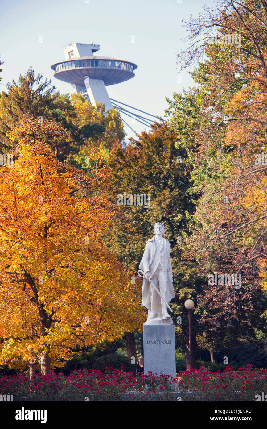 Autunno umore vista parco cittadino e colorati di foglie di autunno su enormi alberi, statua di Janko Kral nella parte anteriore e UFO Tower bridge architettura sul retro Foto Stock