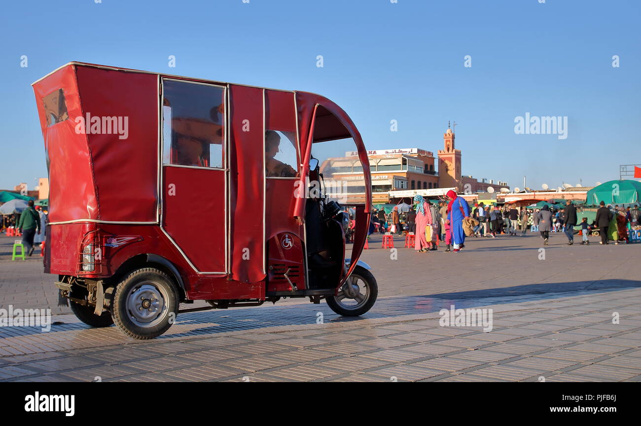 Piazza Principale del mercato chiamato Piazza Jamaa El Fna a Marrakech, Marocco, rosso piccolo locale tipico taxi tuk-tuk, persone facendo aily shopping.view Foto Stock