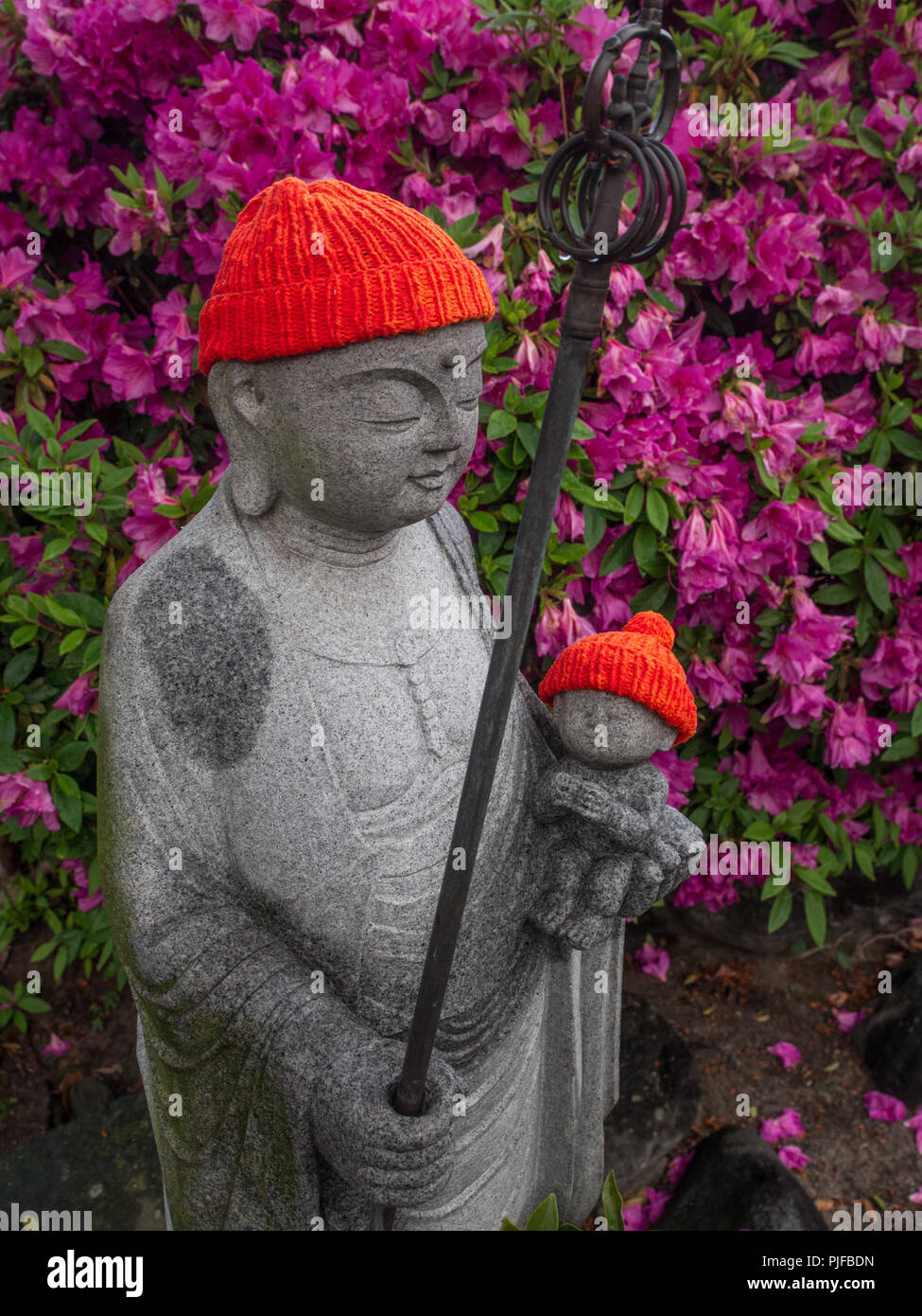 Jizo statua con bambino e cappuccio rosso, azealia in Bloom, Enmeji tempio, henro no Michi sentiero del pellegrino, Ehime Shikoku Giappone Foto Stock