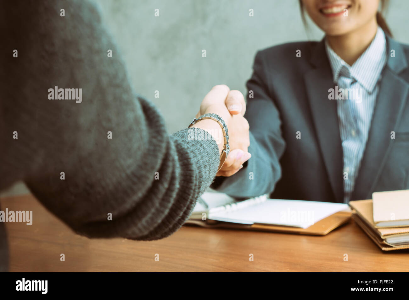 Due Asian imprenditrici stringono le mani su una scrivania come loro di chiudere una trattativa o di partenariato, la messa a fuoco a mani del giovane donna asiatica Foto Stock