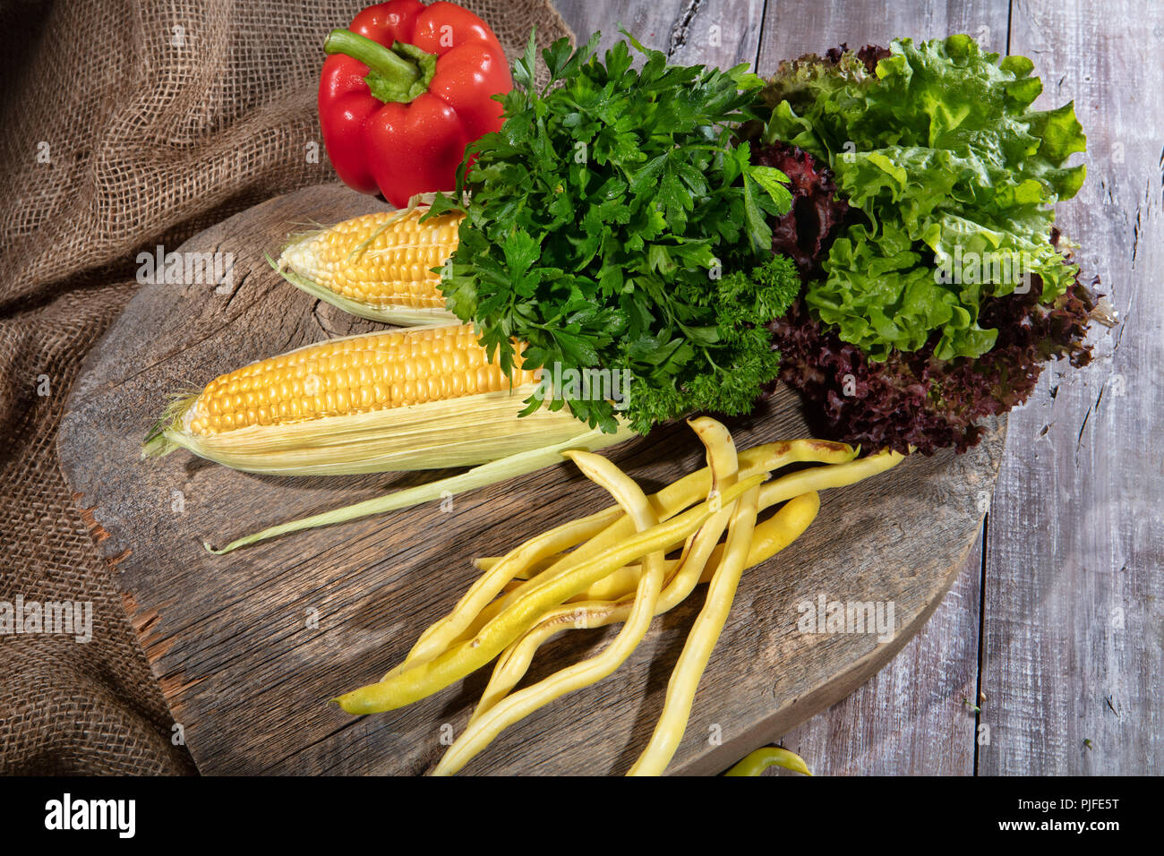 Il mais, verde pisello e pomodoro su un tavolo di legno Foto Stock