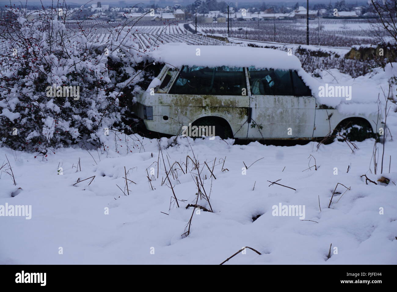 Un distrutto abbandonato il vecchio arrugginito in auto il paese su un tempestoso giorno nevoso nella Valle della Loira, Francia Foto Stock