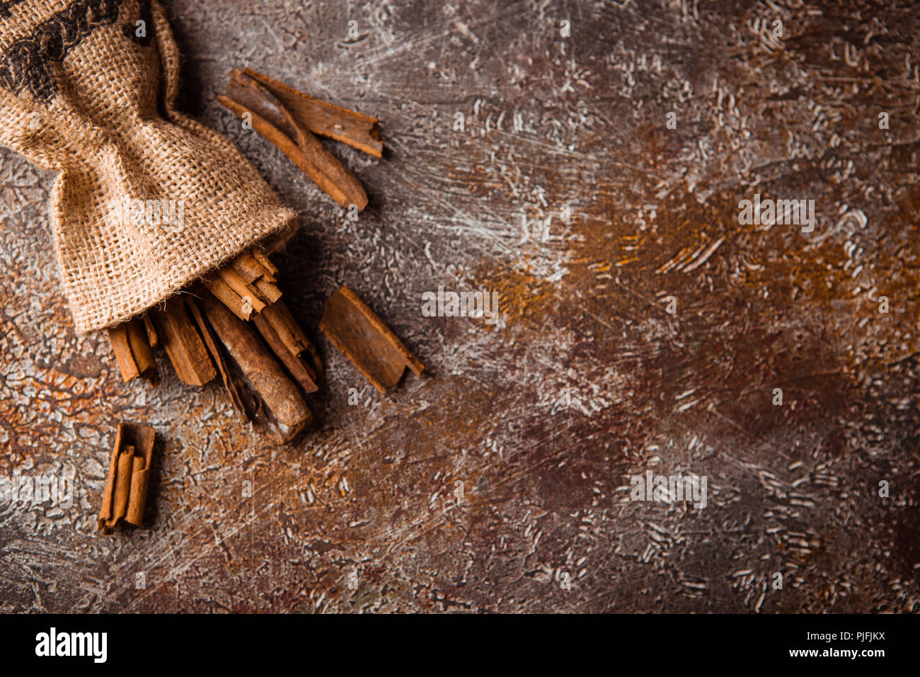 Bastoncini di cannella in una borsa di tela su grunge backround marrone Foto Stock