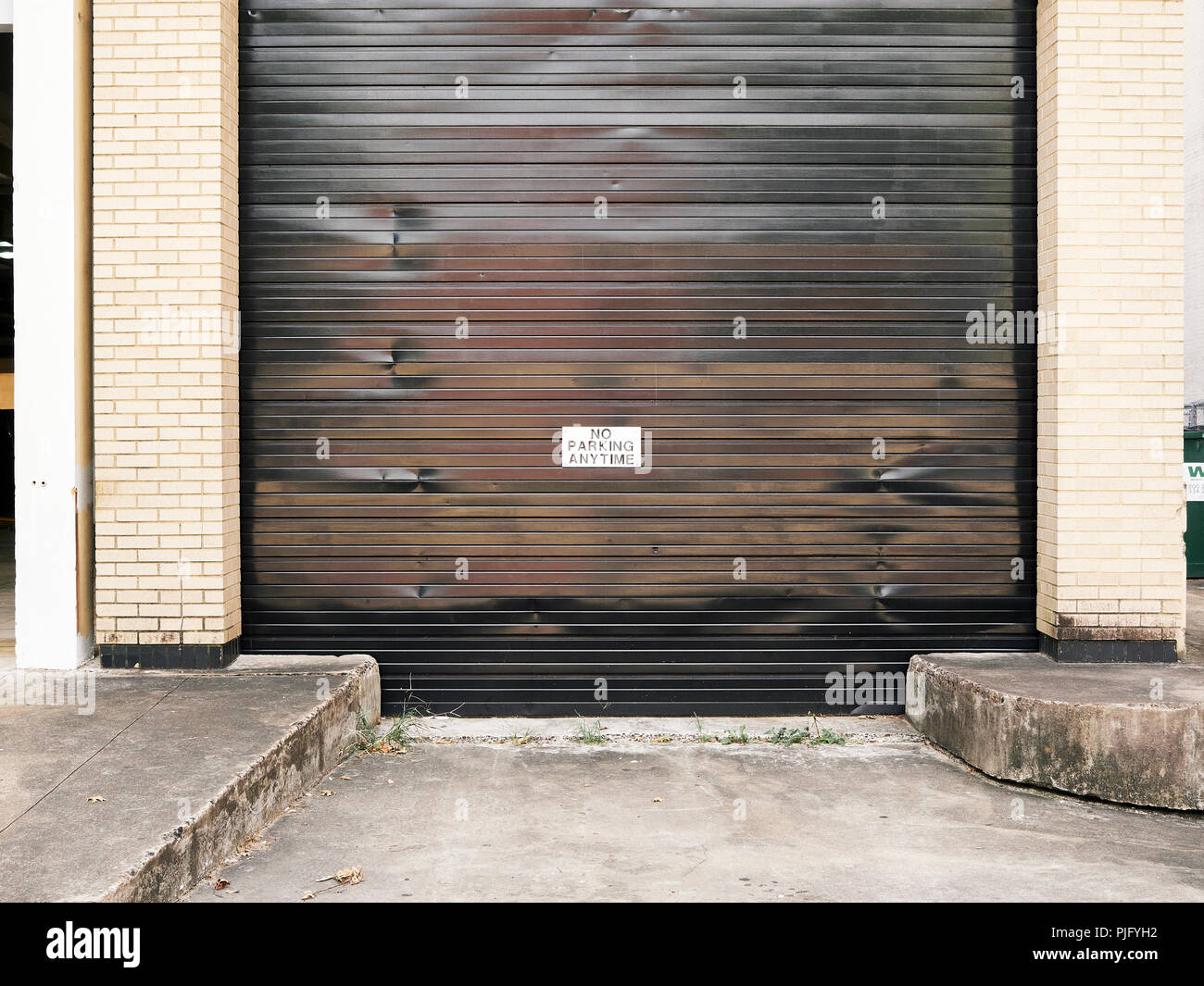 Nessun parcheggio qualsiasi tempo segno di avvertimento pubblicato Il grande rullo ricevente parte superiore porta del garage sulla strada di città a Montgomery in Alabama, Stati Uniti d'America. Foto Stock