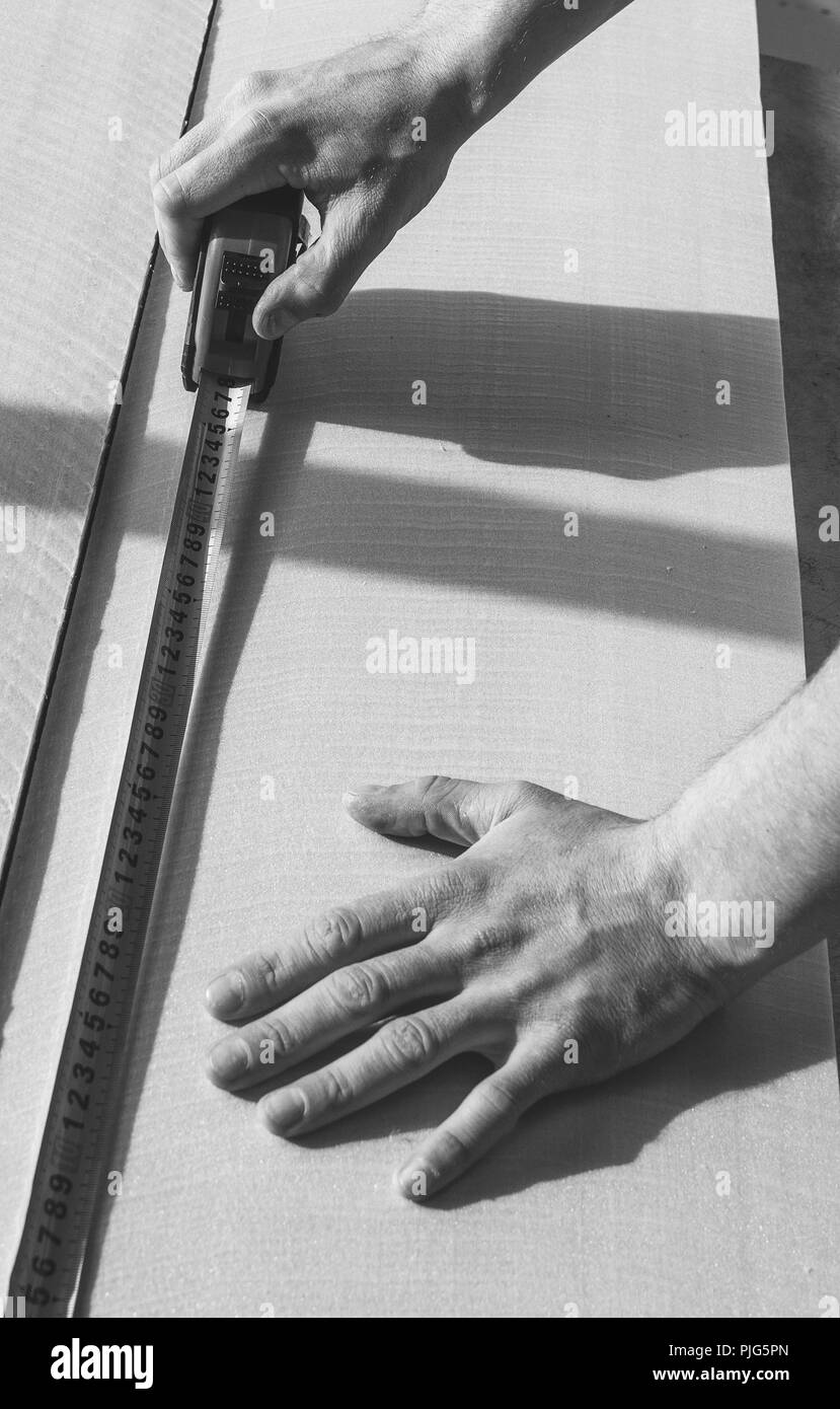 Un uomo fa un nastro di marcatura su di un foglio di prova di suono e materiale isolante termico, foto in bianco e nero Foto Stock