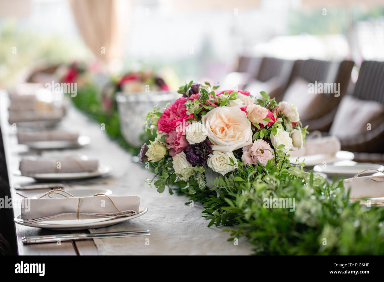 Ordinatamente intrecciati in un tubo sala da pranzo igienico decorate con un rametto di pistacchio. Banchetti per matrimoni o cene di gala. Il tavolo e sedie per gli ospiti, Servita con posateria e stoviglie. party sulla terrazza Foto Stock