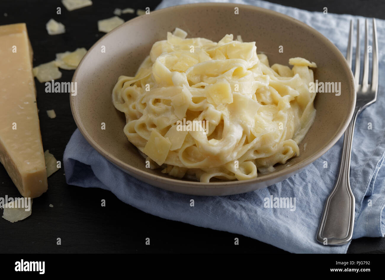 Fettuccine Alfredo con formaggio parmigiano su un tavolo rustico Foto Stock