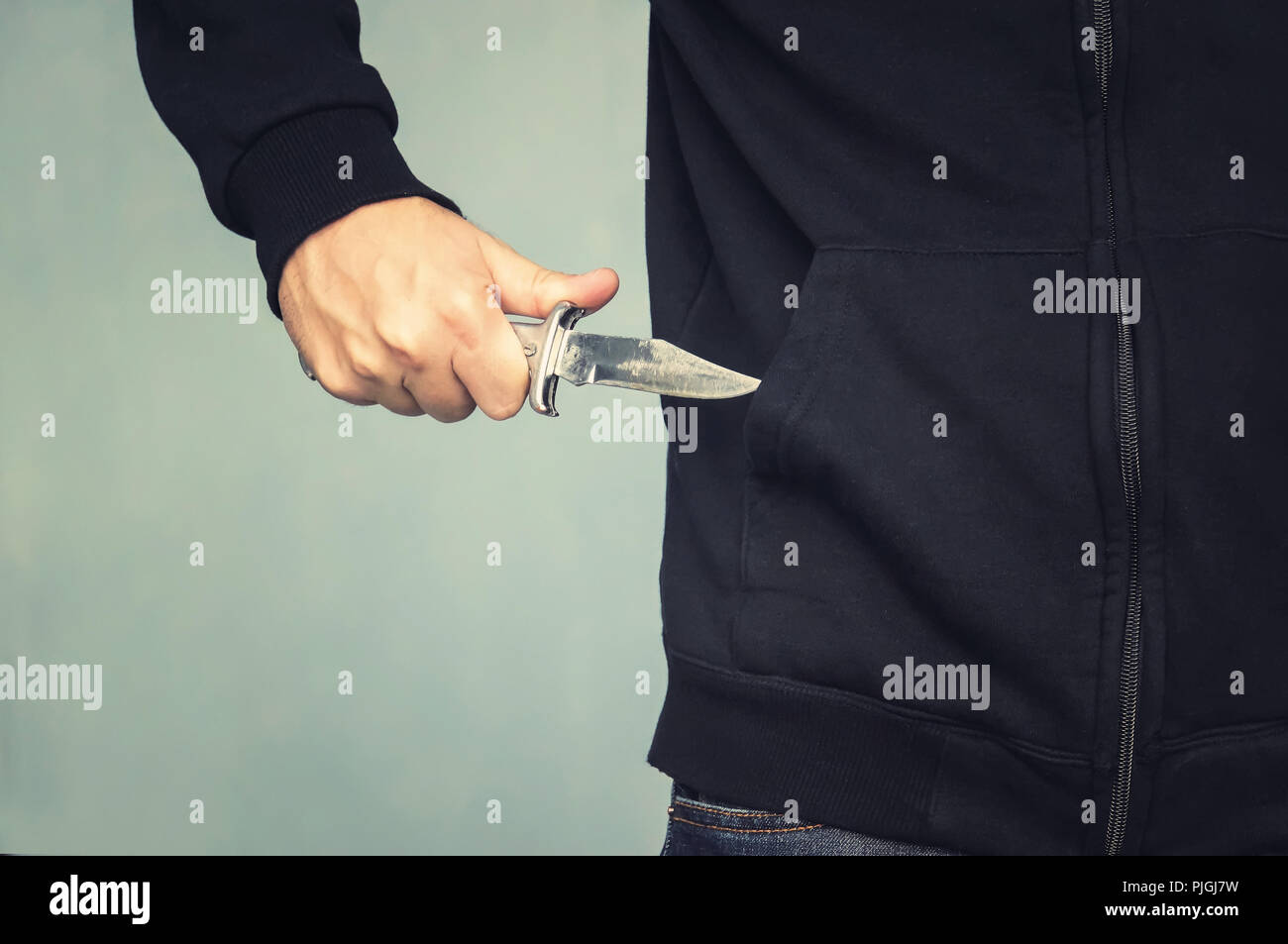 Un maniaco con un coltello in tasca. L'assassino nasconde un piccolo coltello pieghevole. Intimidazione con un coltello nella rapina. mafia. Foto Stock