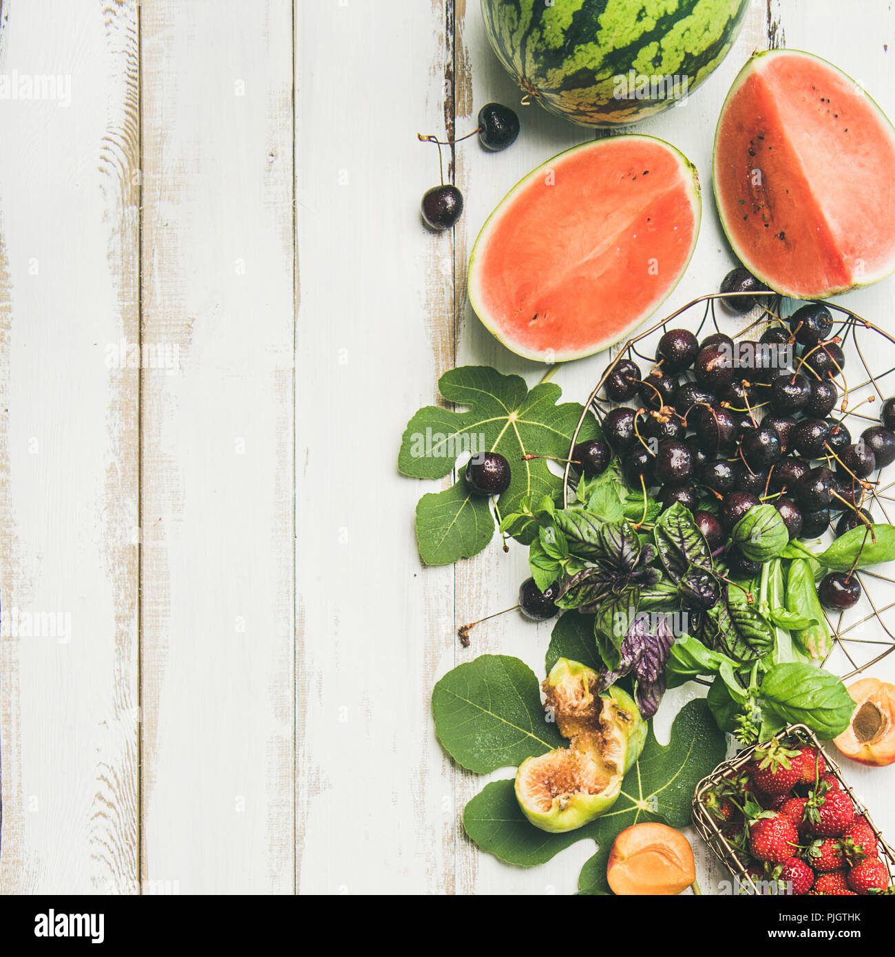 Estate sfondo alimentare. Flat-lay stagionale di frutta e verdura e verdi su bianco sullo sfondo di legno, vista dall'alto, spazio copia, quadrato raccolto. Vegetariano, Foto Stock