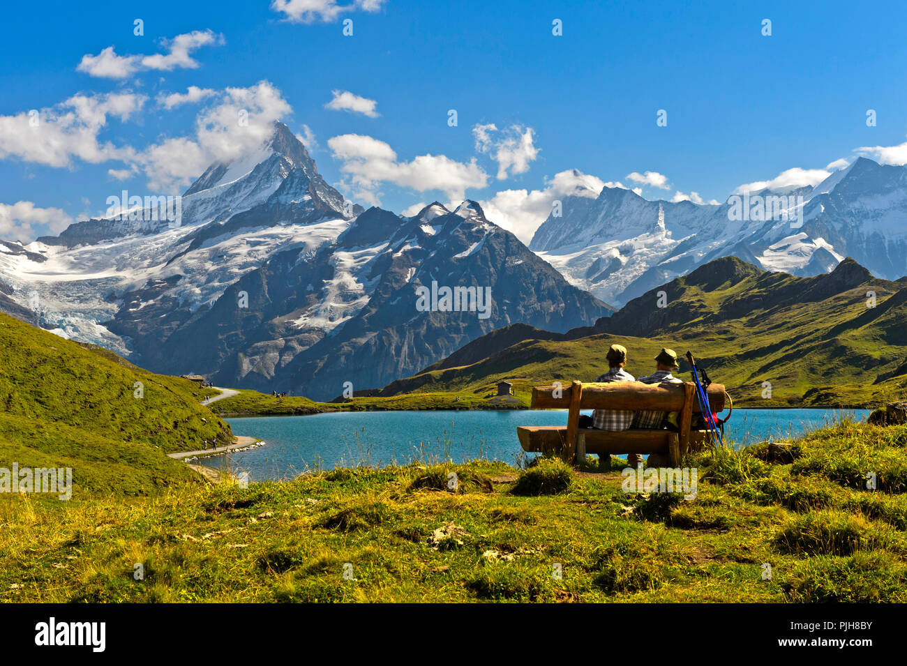 Gli escursionisti mettendo in pausa su una panca di legno al lago Bachalpsee, dietro i vertici Schreckhorn e Finsteraarhorn, Grindelwald Foto Stock