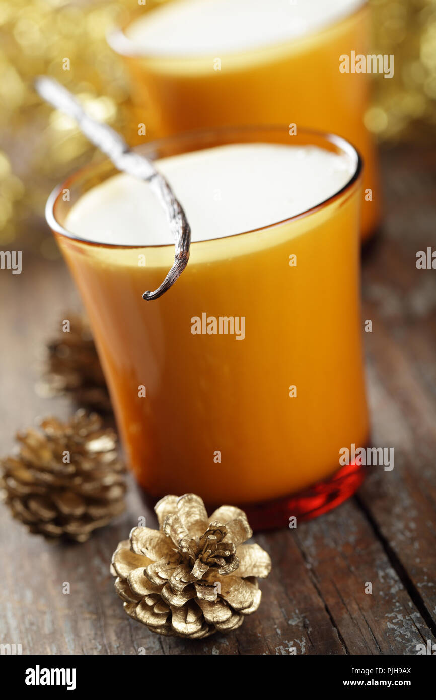 Zabaione in vetro giallo con il baccello di vaniglia e le decorazioni di Natale Foto Stock