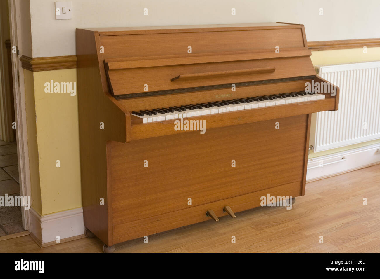 Anni Settanta acustica di legno Schreiber pianoforte su pavimento in laminato nel salotto di casa Foto Stock