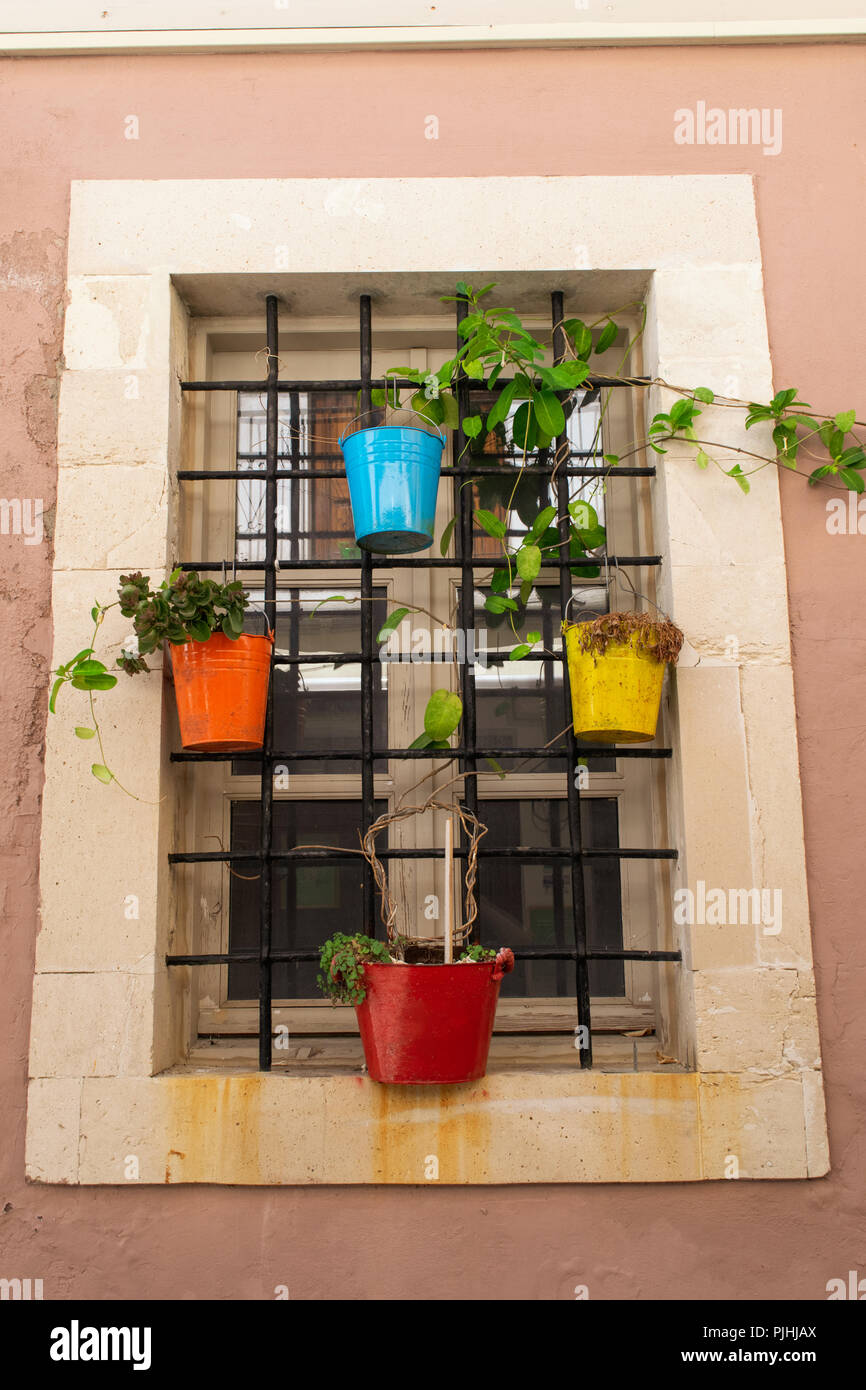 Finestra con fiori colorati vasi attaccato alle sbarre di ferro. Città vecchia, Creta, Grecia Foto Stock