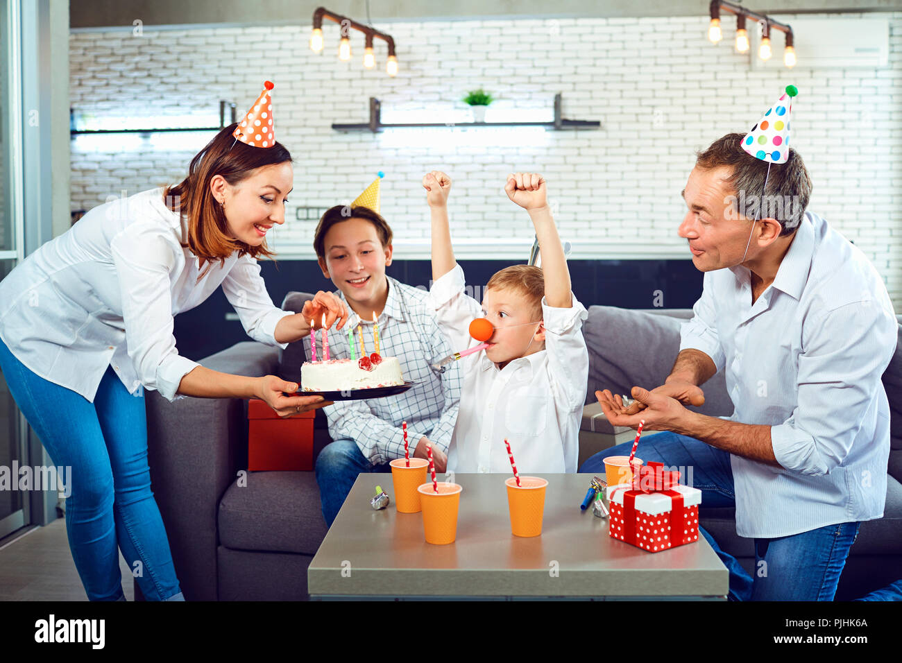 Una famiglia con una candela torta celebra un compleanno. Foto Stock