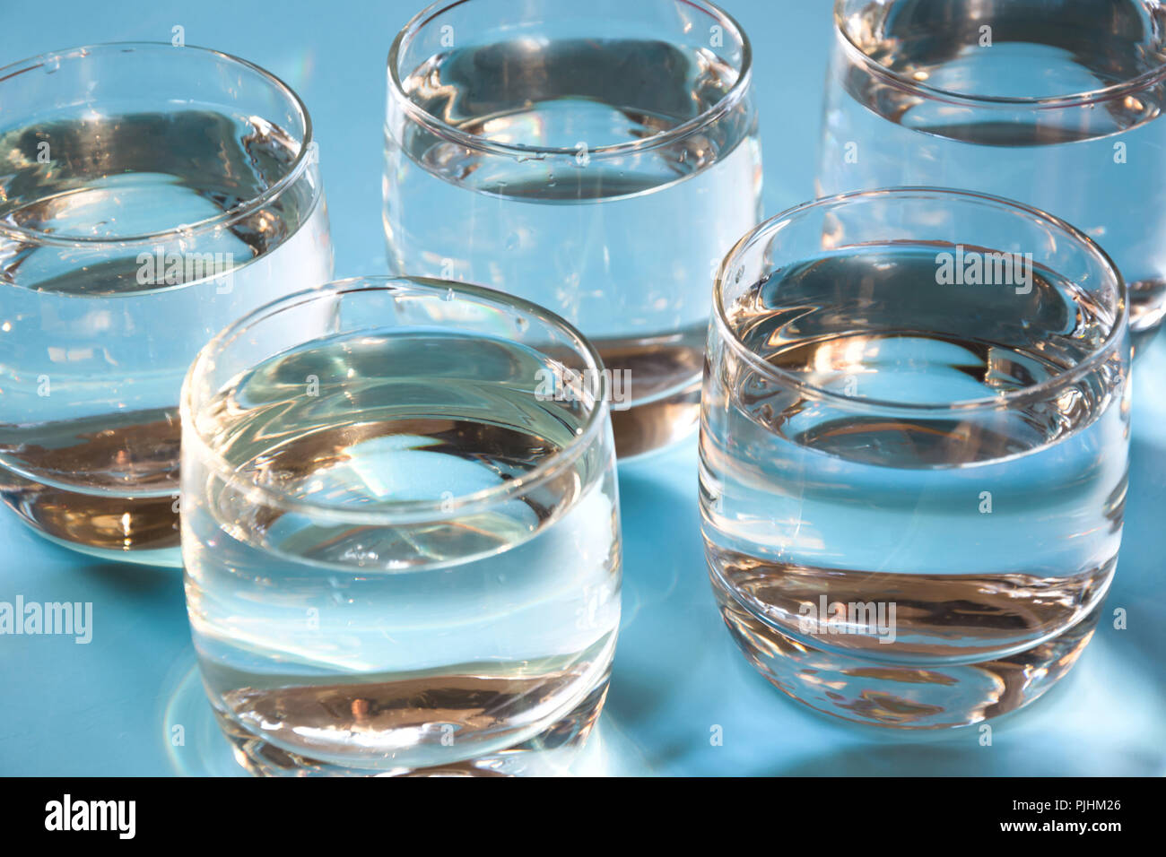 Bicchieri di acqua sul pastello blu. Bilancio idrico per un sano. Pattern. Foto Stock
