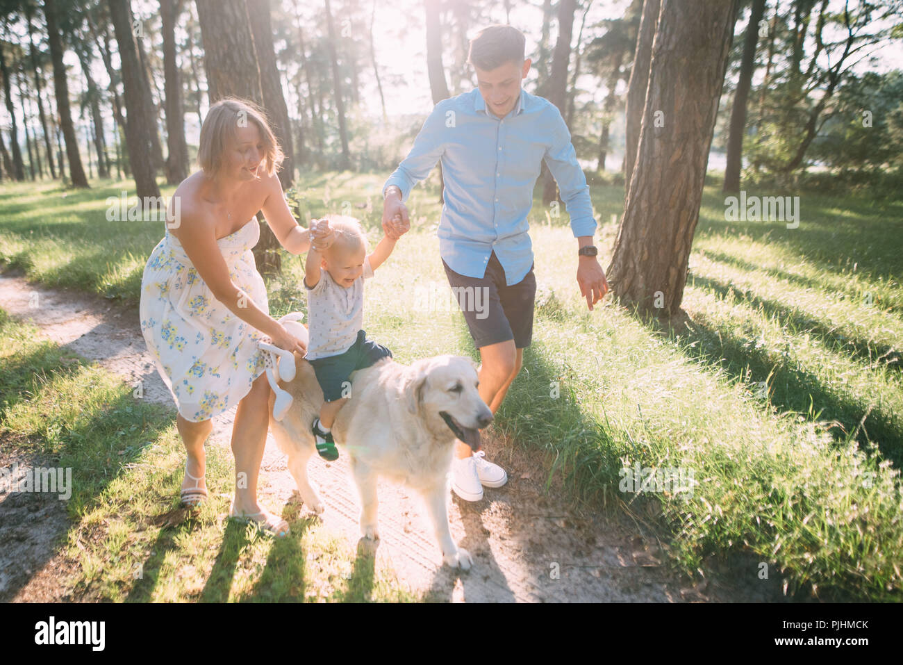 Una simpatica famiglia - mamma, papà e figlio spendere tempo di divertimento all'aperto con il loro cane Foto Stock