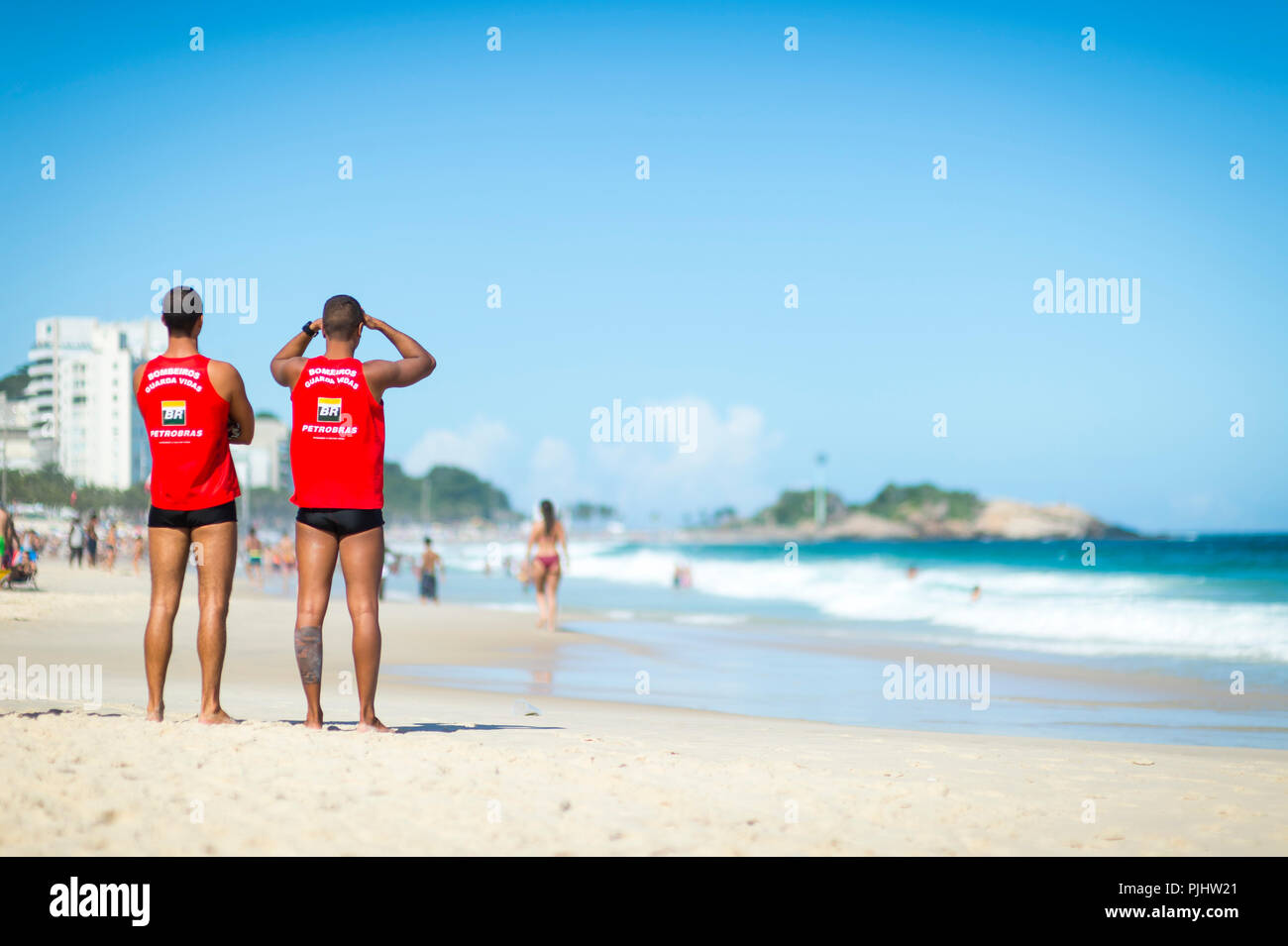 RIO DE JANEIRO - circa marzo, 2018: Coppia atletico di vita delle guardie in uniforme guarda la pesante surf sulla spiaggia di Ipanema Foto Stock