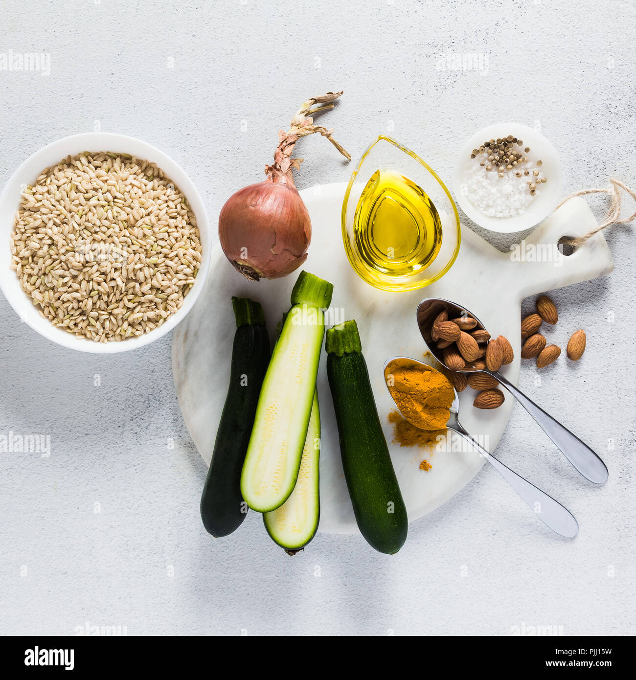 Ingredienti per il risotto con il riso integrale con zucchine e curcuma sul tavolo. Una sana italiana cucina vegana Foto Stock