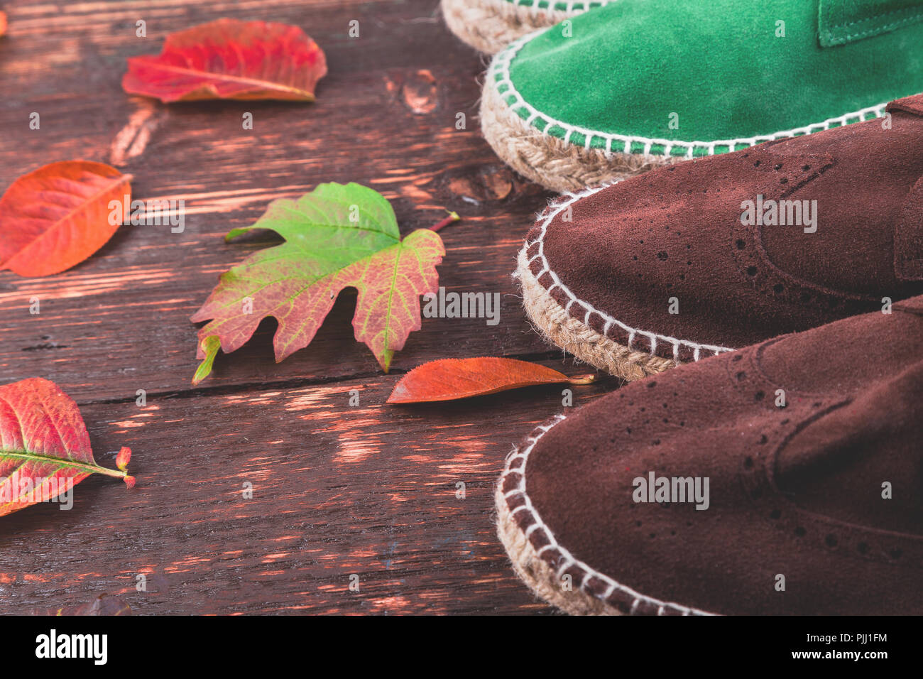 Marrone e verde uomo stivali in pelle scamosciata " espadrilles " su sfondo  di legno con foglie. In autunno o inverno scarpe. due coppie. Lay piatto  Foto stock - Alamy