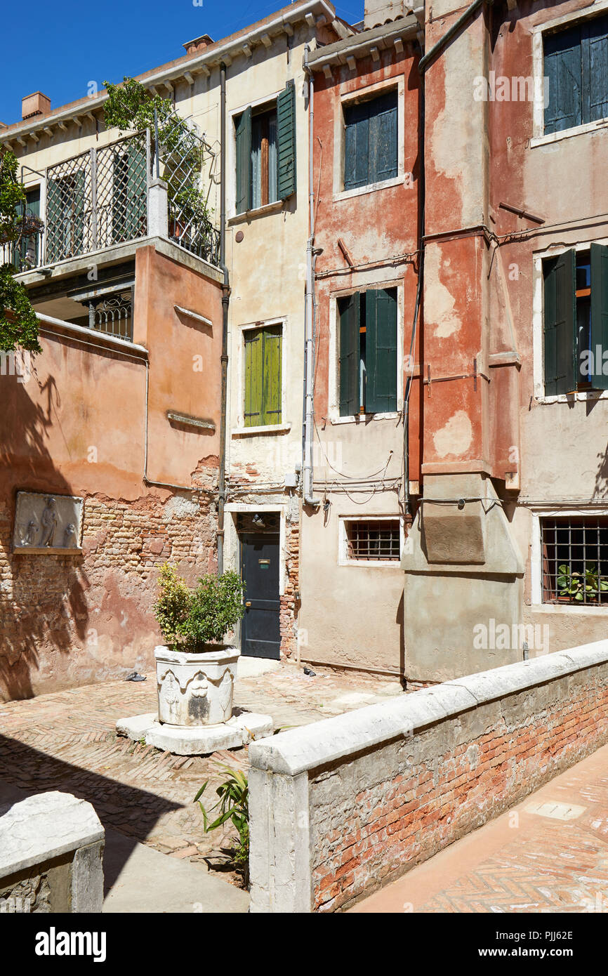 Tribunale di Venezia con antico pozzo di acqua, edifici e case di facciate in una giornata di sole in Italia Foto Stock