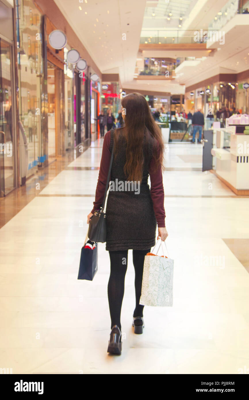 Vista sul retro di una giovane donna che fa shopping nel centro commerciale Foto Stock