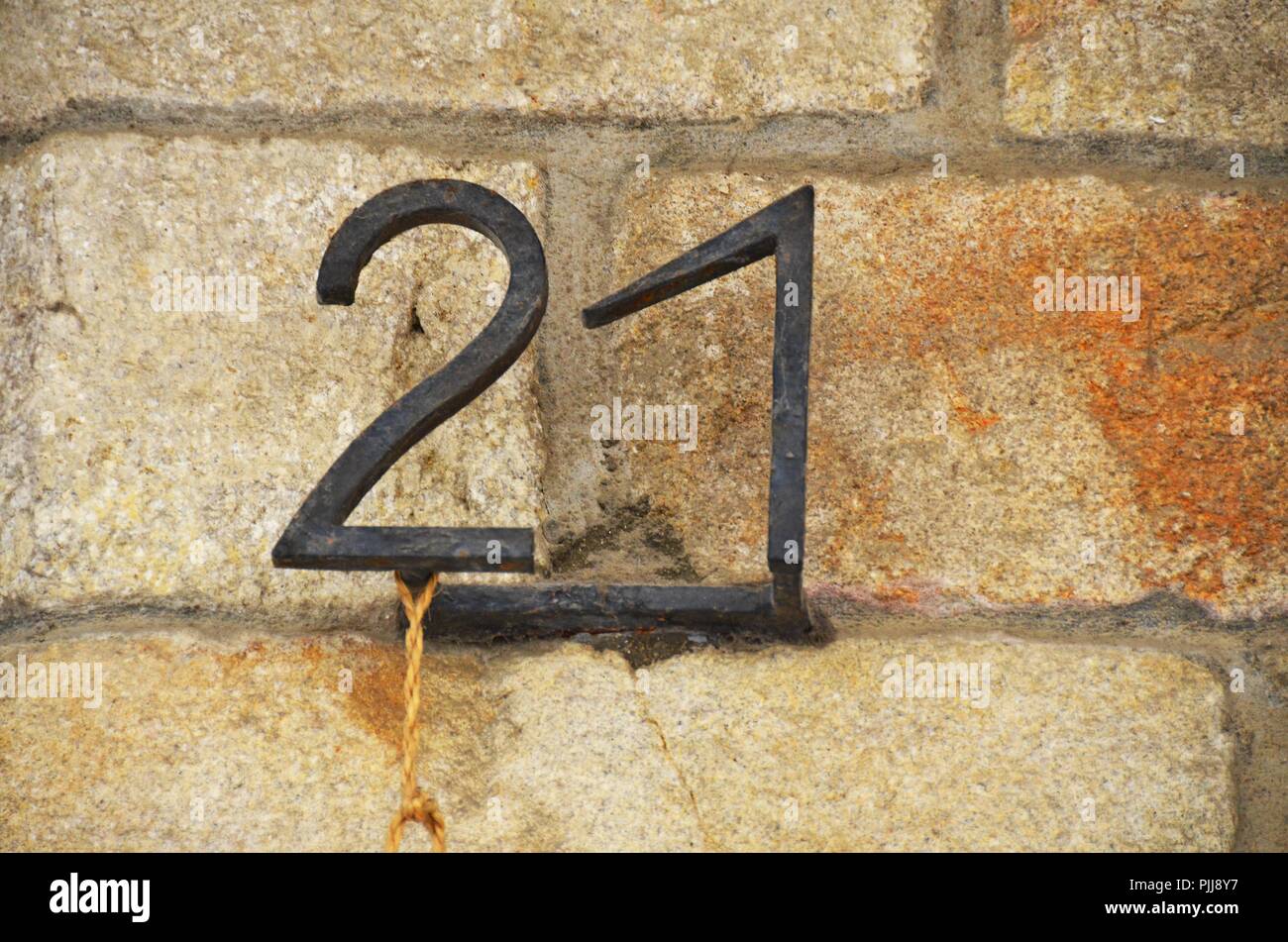 Il numero civico 21 sul vecchio rustico in pietra arenaria parete in mattoni, due arrugginito in ferro battuto i numeri di metallo Foto Stock