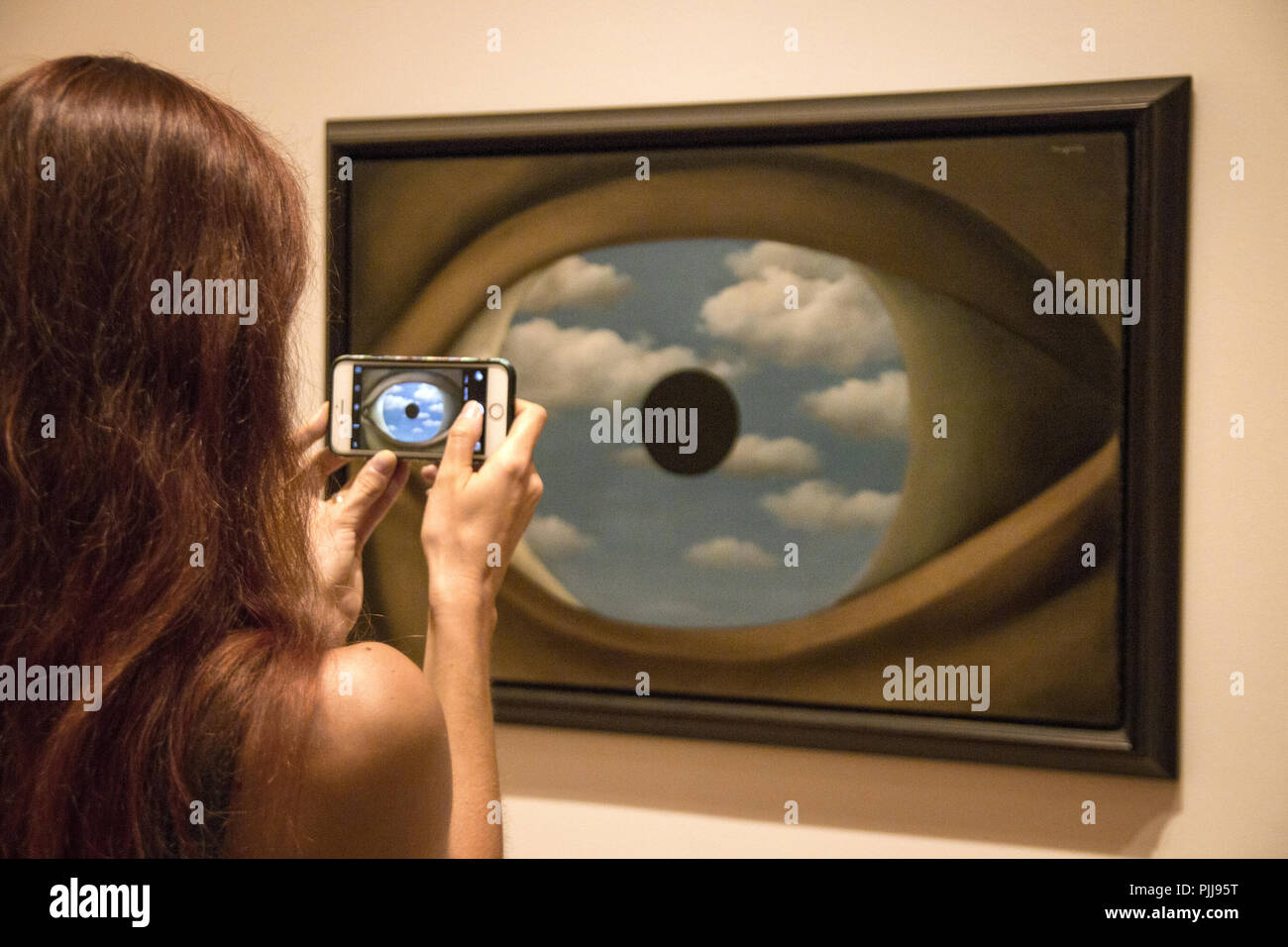 Ragazza con il cellulare sta scattando una foto di un famoso dipinto in galleria d'arte, enorme occhio umano a colori del cielo blu, il False Mirror, MoMA New York Foto Stock