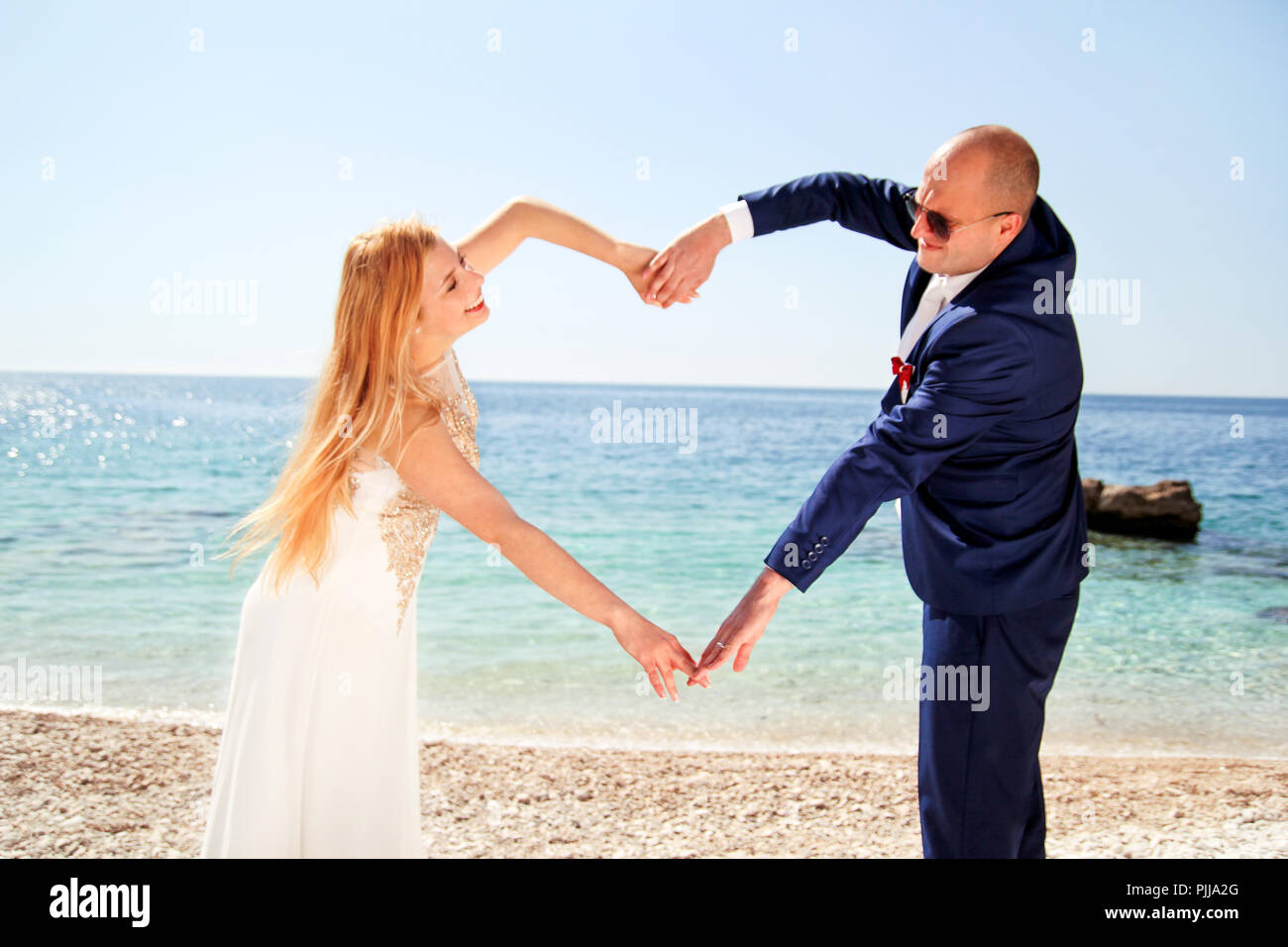 Nozze. Nozze sposò coppia di mani fanno un vero cuore. Coppia felice giorno matrimonio. Bella Sposa e lo sposo in spiaggia. Allegro coppia sposata. Foto Stock
