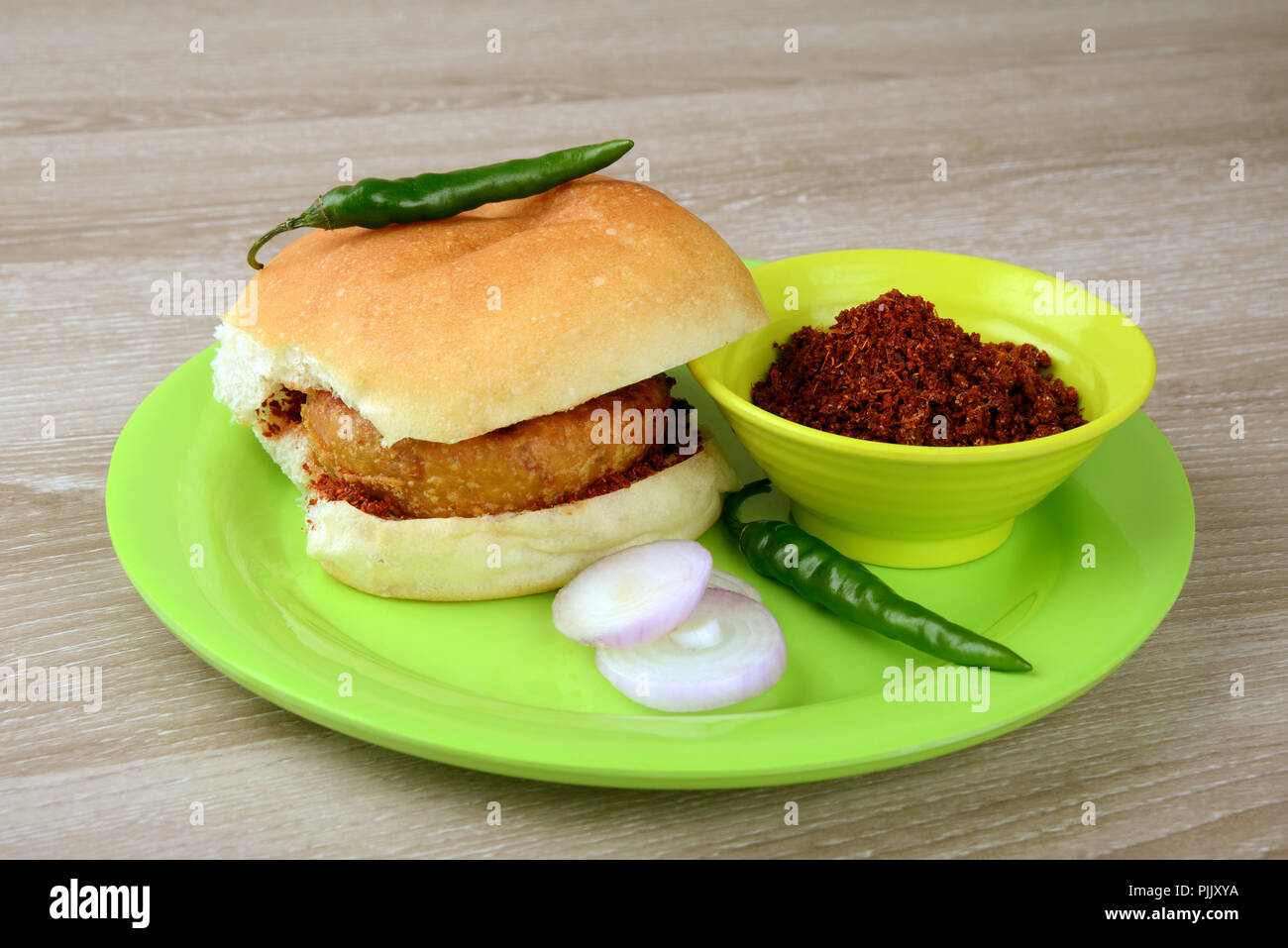 Vada Pav con fette di cipolla peperoncino verde e chutney di aglio, una rinomata cucina di strada in India Foto Stock