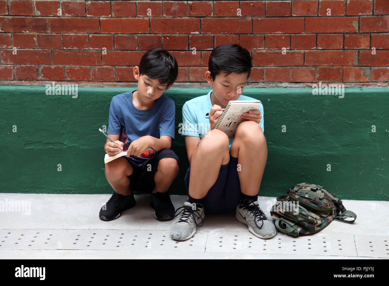 2 ragazzi stanno facendo la loro homeworks su strada Foto Stock