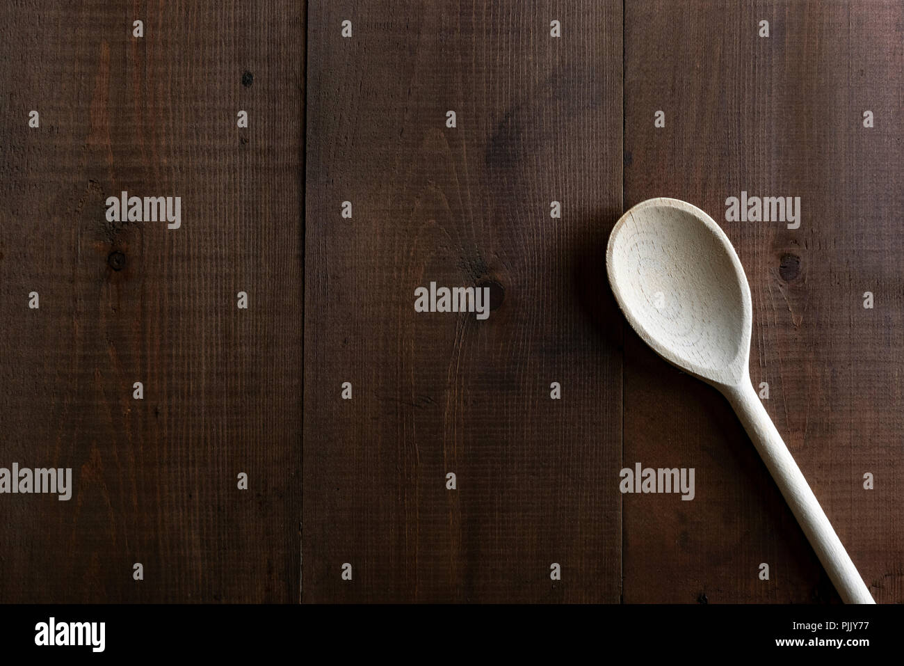 Tradizionale cucchiaio di legno su un bordo scuro dello sfondo. Foto Stock