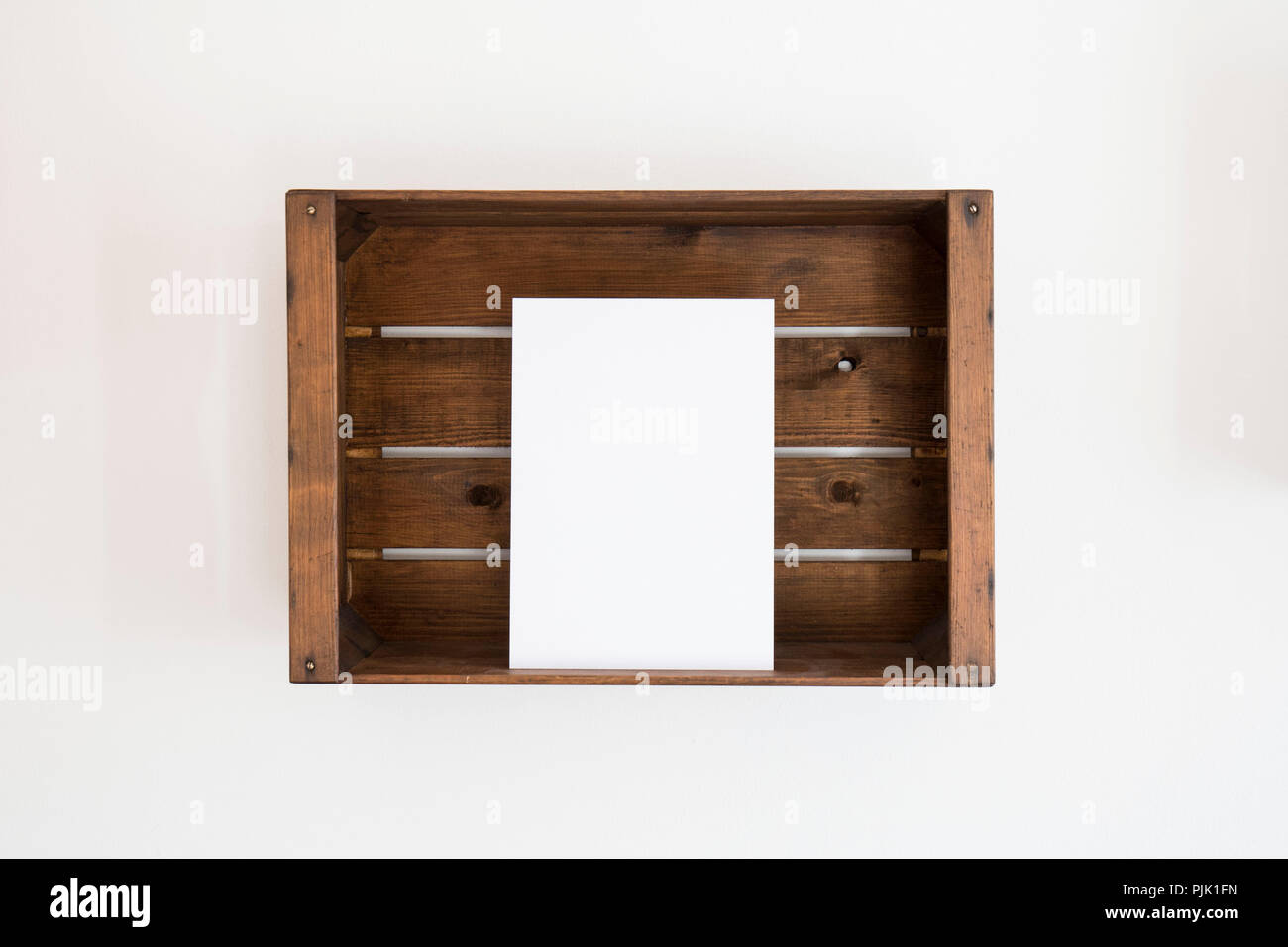 Una scatola di legno con un foglio di carta bianco edgewise Foto Stock