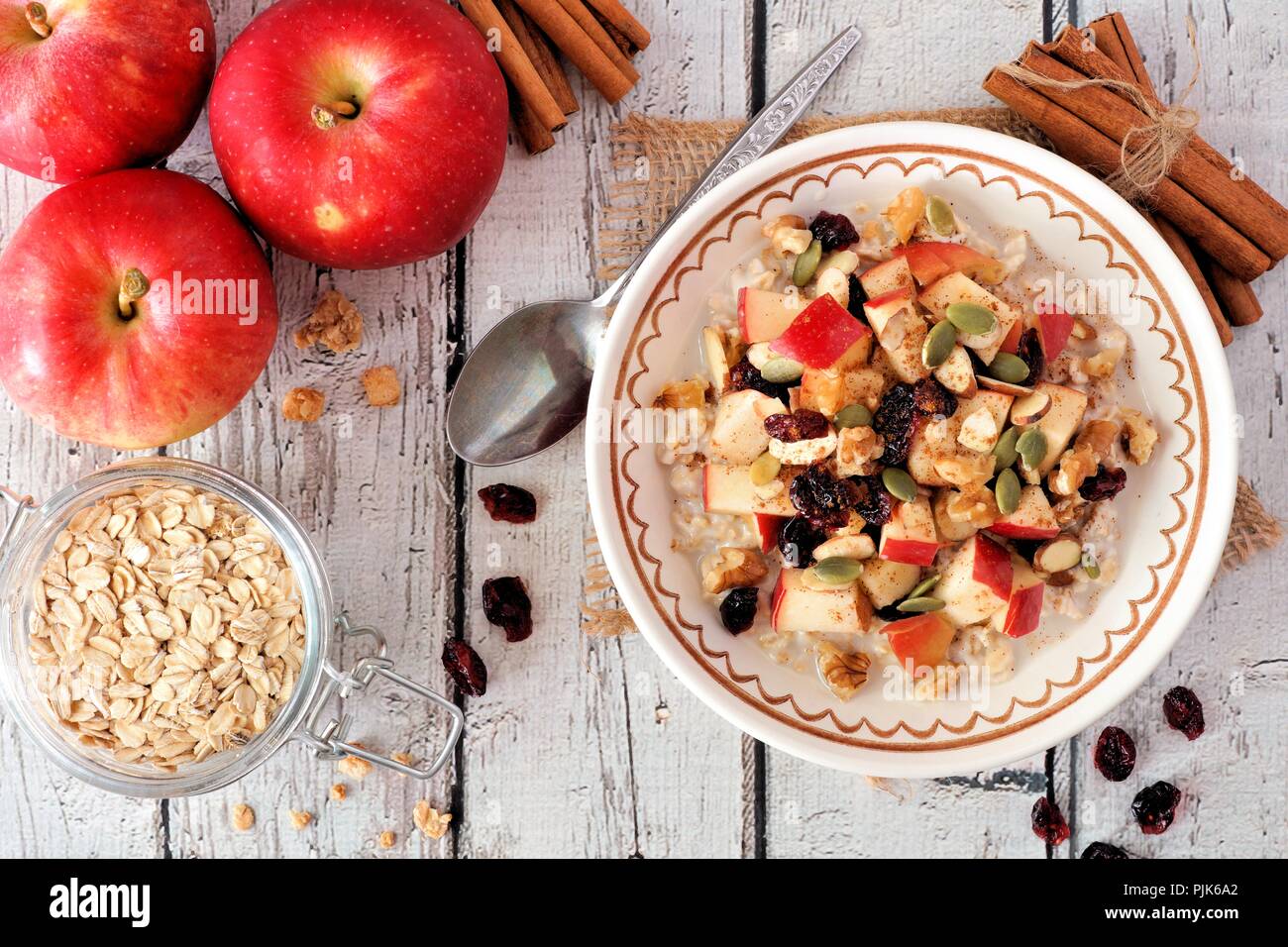 In autunno la prima colazione i fiocchi d'avena con mele, mirtilli rossi, le sementi e i Dadi, al di sopra della scena sul bianco rustico tavolo in legno Foto Stock