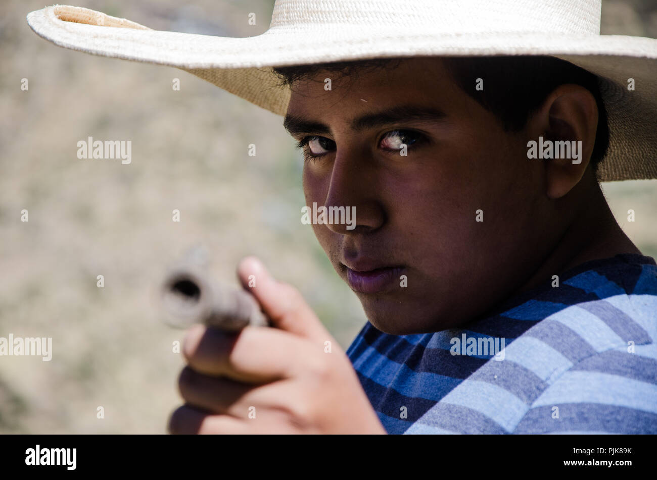 Vicino la faccia del ragazzo con cappello rivolto con un fucile Foto Stock
