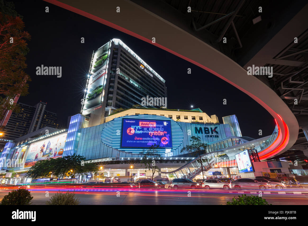 Inceppamento di traffico su occupato Phayathai Road e MBK Centre shopping mall e altri edifici nel centro cittadino di Bangkok, Thailandia, di notte. Foto Stock