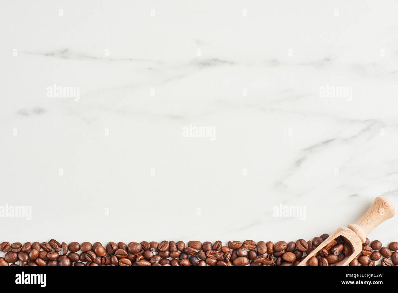 I chicchi di caffè e scoop di legno su sfondo marmo con copia spazio. Lay piatto Foto Stock