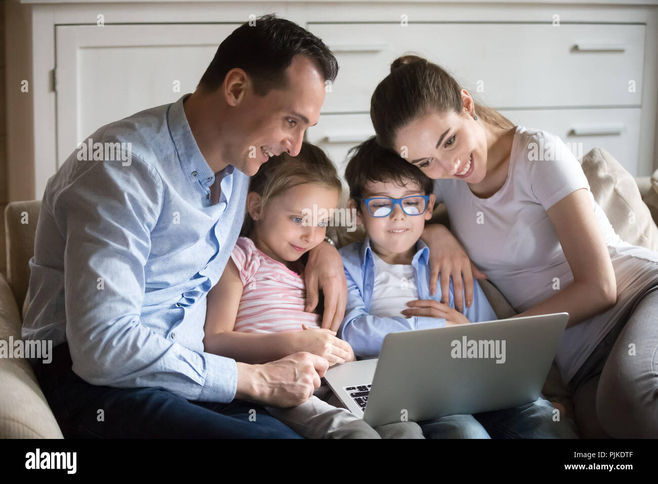 Coccolare i genitori con bambini piccoli a guardare cartoon su laptop Foto Stock