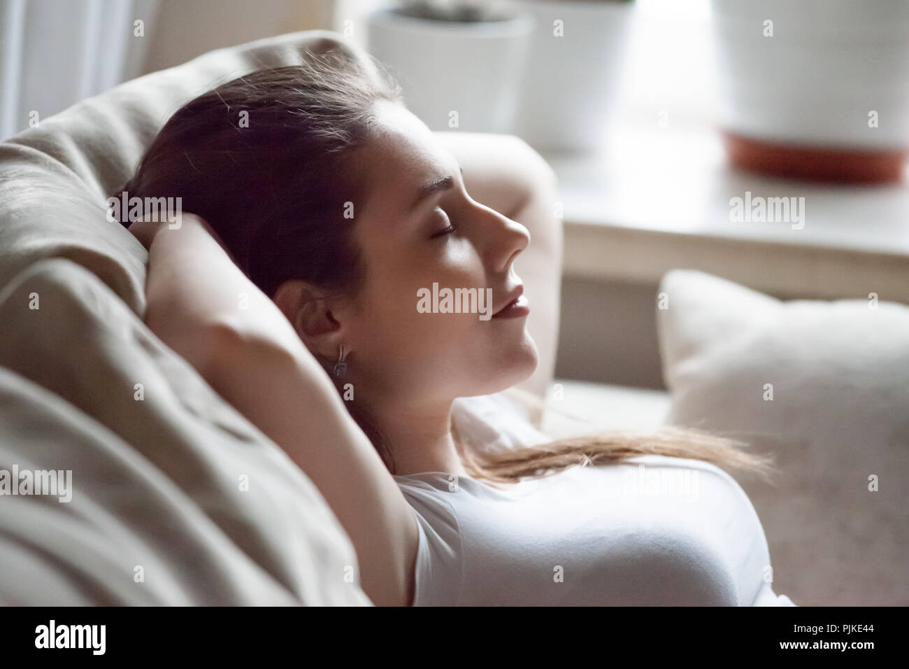 Donna calma rilassante sul divano le mani sopra la testa Foto Stock