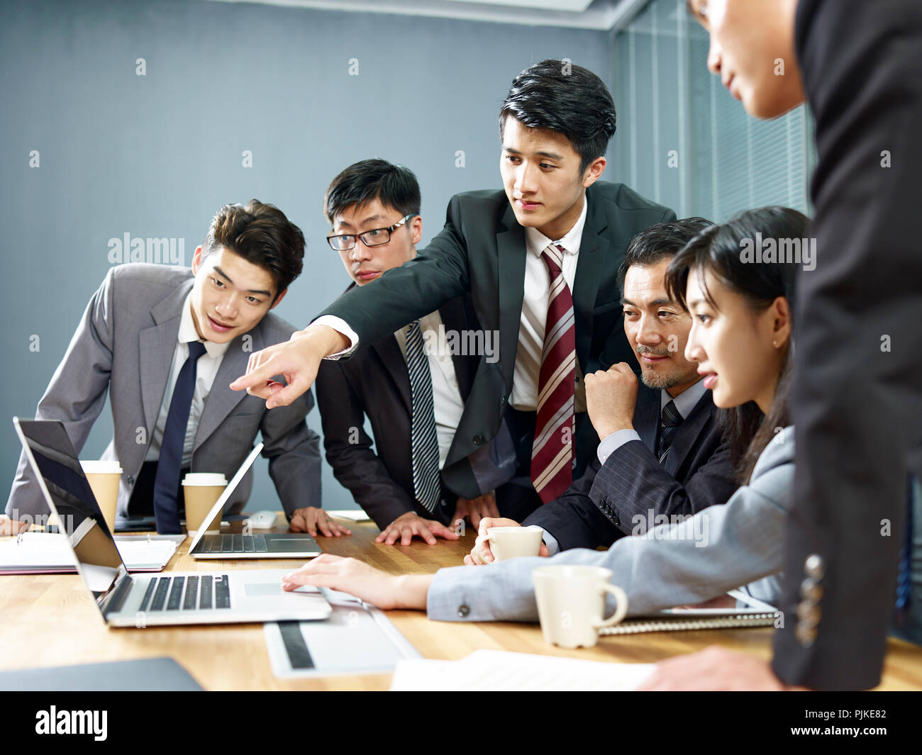 Un team di asian business Dirigenti uomini e donne che lavorano insieme in ufficio utilizzando il computer portatile. Foto Stock