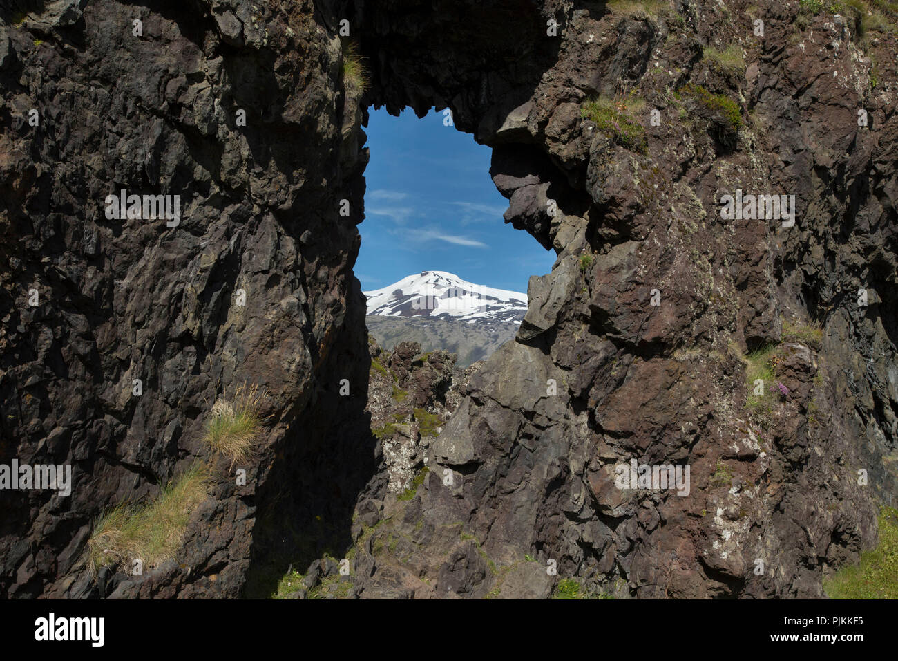 L'Islanda, la spiaggia di Dritvik, vulcano Snaefellsjökull visibile attraverso una finestra di roccia Foto Stock