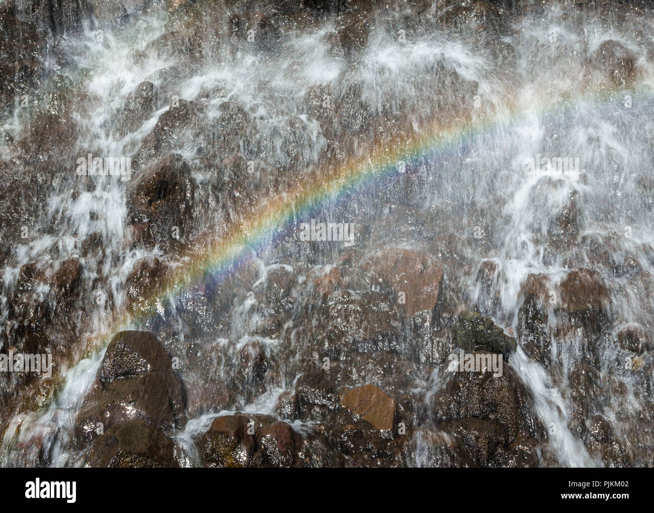 L'Islanda, cascata, dettaglio con arcobaleno, spruzzi d'acqua, pietre rosse Foto Stock