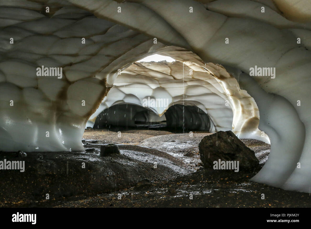 L'Islanda, neve grotta lavato dal flusso di acqua che fluisce dal soffitto Foto Stock