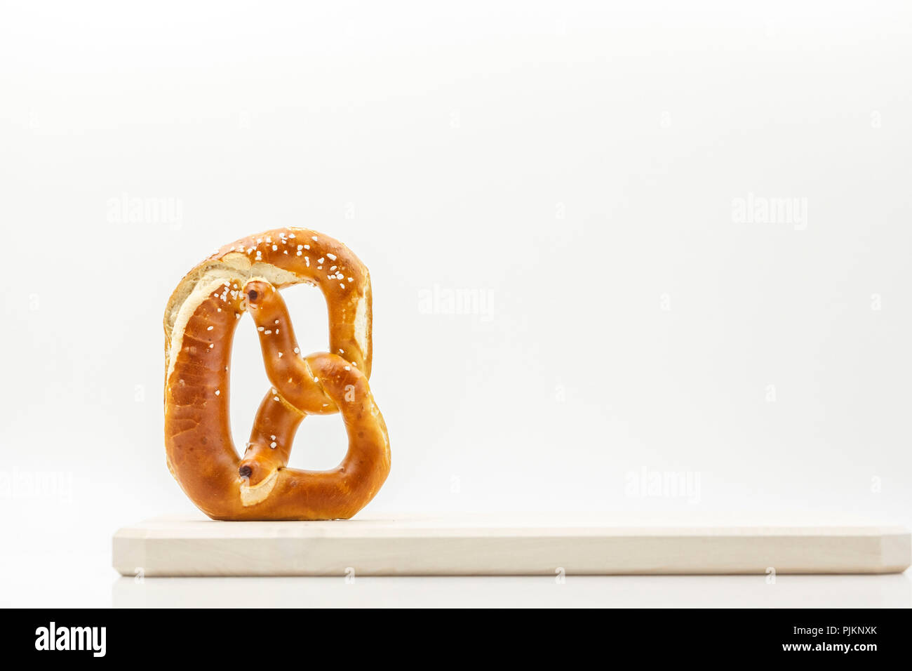 Un pretzel, posto su una tavola di legno contro uno sfondo luminoso, la lettera "B" come la Baviera o Brezn, Foto Stock